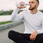 A man in sportswear hydrates outdoors, promoting healthy lifestyle and fitness.