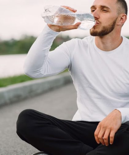 A man in sportswear hydrates outdoors, promoting healthy lifestyle and fitness.