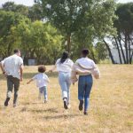 Cheerful family walking together in a sunny park surrounded by trees.