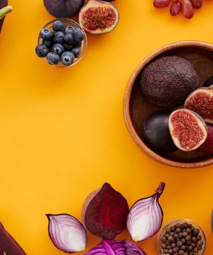 Colorful assortment of fruits, vegetables, and herbs on a vibrant yellow background in a flat lay style.