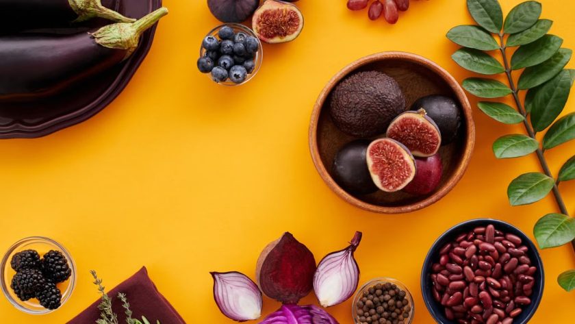 Colorful assortment of fruits, vegetables, and herbs on a vibrant yellow background in a flat lay style.